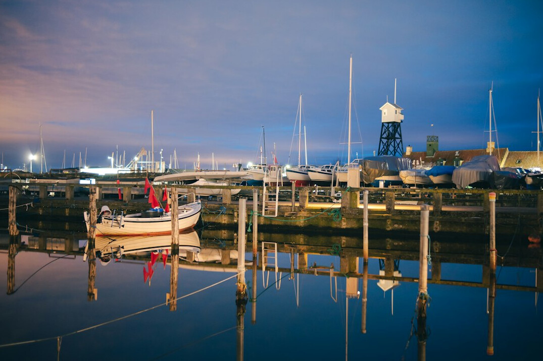 Elderly Danish fisherman mending nets on his boat at dawn