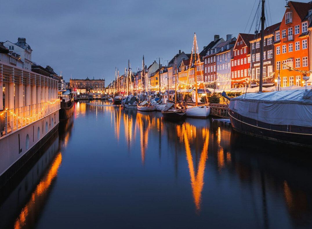 Colorful harbor houses reflected in canal water at dusk in Copenhagen